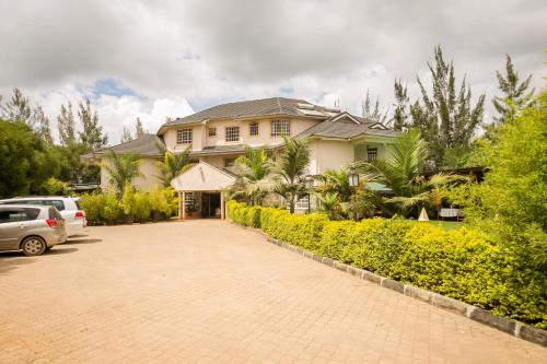 a house with a car parked in front of a driveway at Hotel Rudi in Nairobi