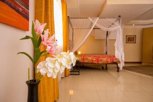 a bedroom with a bed and flowers in a room at Hotel Rudi in Nairobi