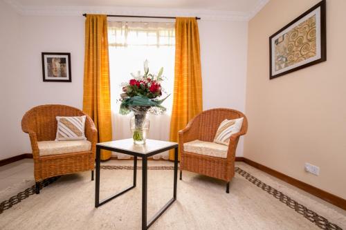 a room with two chairs and a table with a vase of flowers at Hotel Rudi in Nairobi