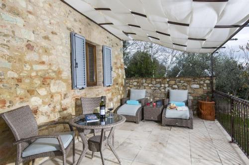 a patio with a table and chairs and a stone wall at Borgo Argiano in Castelnuovo Berardenga