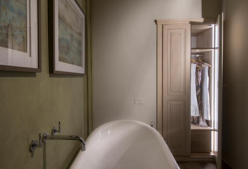 a white bath tub in a bathroom with a closet at Borgo Argiano in Castelnuovo Berardenga