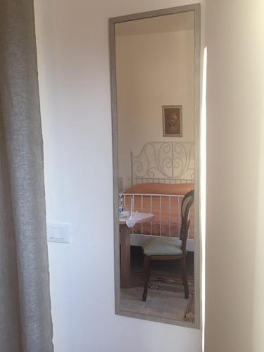 a mirror reflecting a bedroom with a table and a chair at B&B Villa Angela Via della bonifica 17 in Villareia