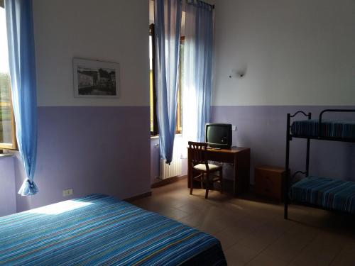 a bedroom with a bed and a desk and a television at ostello ortensi in Farnese