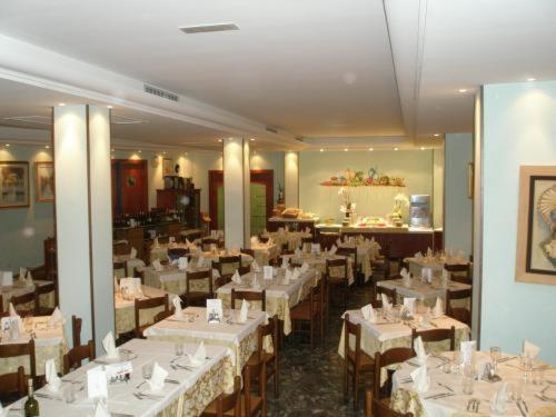 uma sala de jantar com mesas e cadeiras com toalha de mesa branca em Hotel American em Lido di Jesolo
