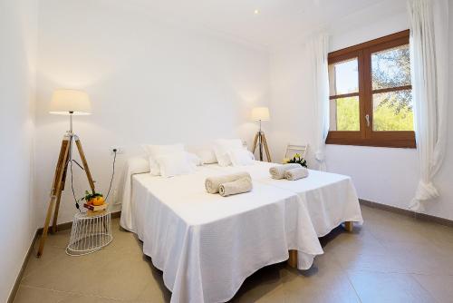a bedroom with a bed with white sheets and a window at Luxury finca Ses Quaranta in Campos