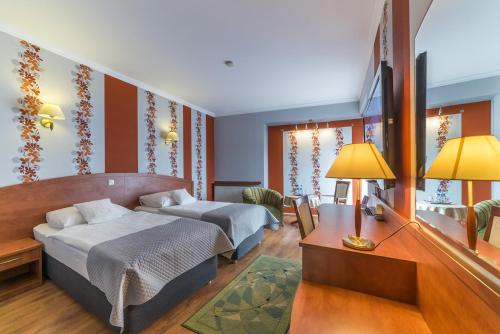 a bedroom with two beds and a desk with a lamp at Hotel Doris in Oborniki