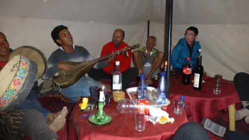 a group of people sitting around a table with a guitar at Auberge Amazigh in Tamtetoucht