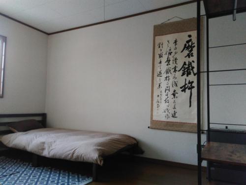 1 dormitorio con 1 cama y una pintura en la pared en The Bohemians' Shelter en Hakuba