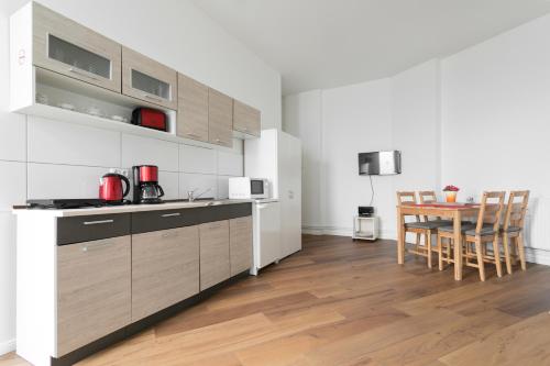 ベルリンにあるCity Studio Apartment for 4, near Sonnenalleeのウッドフロアのキッチン(テーブル、椅子付)