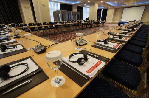 a long table in a conference room with headphones and glasses at Ramada Plaza by Wyndham Gevgelija in Gevgelija