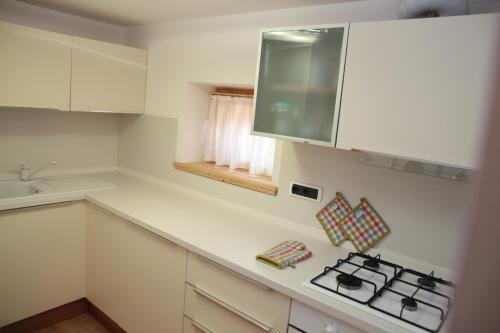 a kitchen with white cabinets and a stove top oven at Albergo diffuso Valcellina e Val Vajont in Claut in Claut