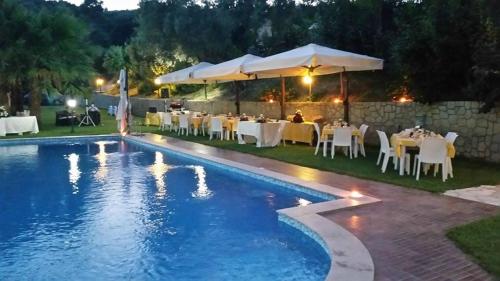 a pool with tables and chairs next to a restaurant at Agriturismo La Valle Incantata Gerace - in Gerace