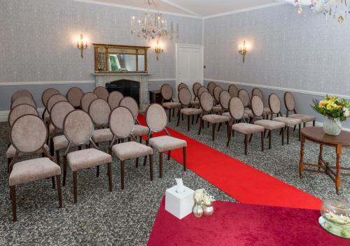 a room with a row of chairs with a red carpet at Flitwick Manor Hotel in Flitwick