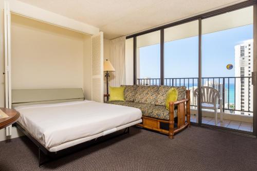 a bedroom with a bed and a couch and a balcony at Hawaiian Sun Holidays in Honolulu