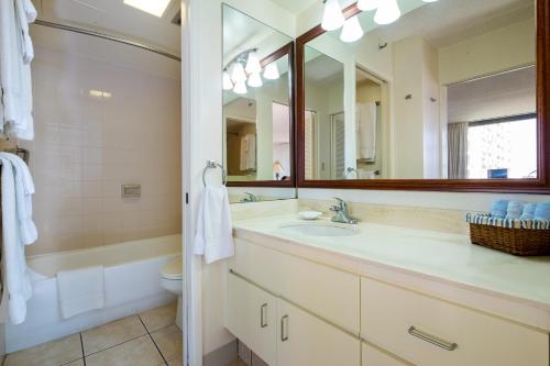 a bathroom with a sink and a tub and a mirror at Hawaiian Sun Holidays in Honolulu