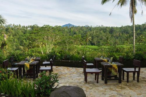 a dining room with tables and chairs and a mountain at Adiwana Dara Ayu Villas in Payangan