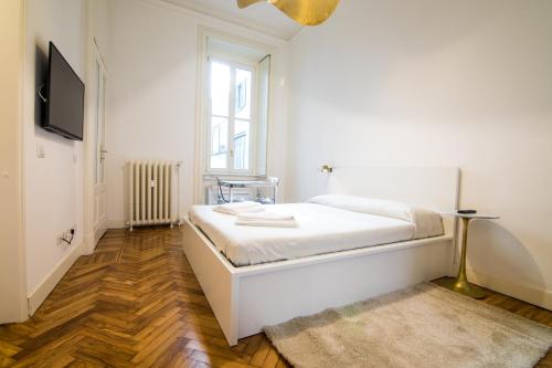 a white bedroom with a bed and a television at Brera Design and Bright Flat in Milan