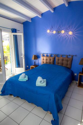 una camera da letto blu con un grande letto blu con due asciugamani di Blue Paradise a Le Gosier