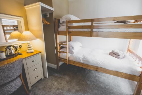 a bedroom with two bunk beds and a desk with a lamp at Kings Arms in Penzance