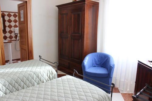 a bedroom with two beds and a blue chair at Villa Cosilinum in Padula