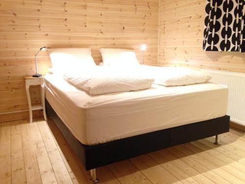 a bed with white sheets and pillows in a room at Midholl guesthouse in Ásmundarstaðir