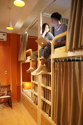 two people sitting on a bunk bed with a laptop at City Hostel Da Nang in Da Nang
