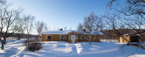 Una casa está cubierta de nieve en un patio. en Villa Kinos, en Utsjoki