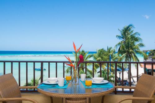 a table on a balcony with a view of the beach at Yellow Bird Hotel in Christ Church