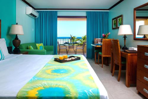 a hotel room with a bed with a view of the ocean at Yellow Bird Hotel in Christ Church