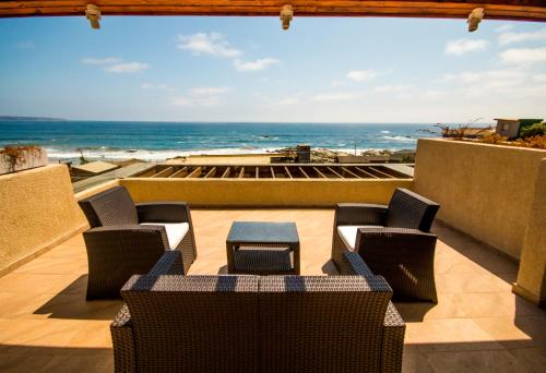a patio with chairs and a table and the ocean at Hotel Mae in Maitencillo
