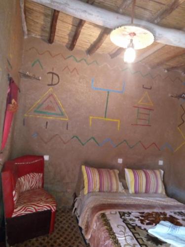 a room with two beds and a wall with drawings on it at Auberge Amazigh in Tamtetoucht