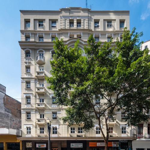 a white building with a tree in front of it at Cinelandia Hotel in Sao Paulo