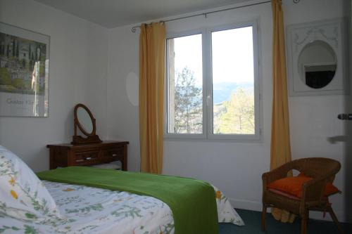 a bedroom with a bed and a window and a chair at Les Rochers in Saint-Étienne-de-Gourgas