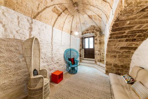 a room with a couch and chairs in a stone wall at Itaca Home to Explorers in Polignano a mare in Polignano a Mare