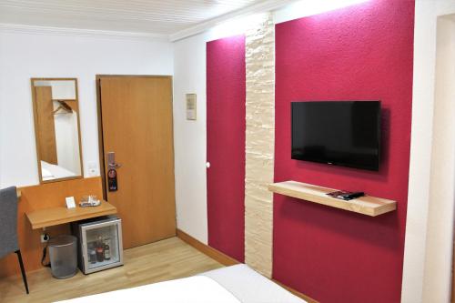 a room with a red wall with a tv on it at Hotel Krone in Pfullendorf