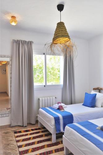 a bedroom with two beds and a chandelier at Siamoformentera Donatella in San Ferrán de ses Roques