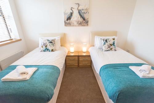 two twin beds in a room with towels on them at Comfortable Modern Apartment in Swindon, FREE parking sleeps up to 5 in Swindon