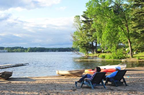 two people sitting in chairs next to a boat on a lake at Sunset Bay Resort in Wisconsin Dells