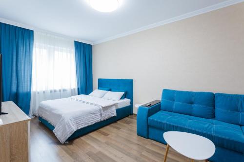 a blue couch and a bed in a room at Cosy Apartment at Pozniaky in Kyiv