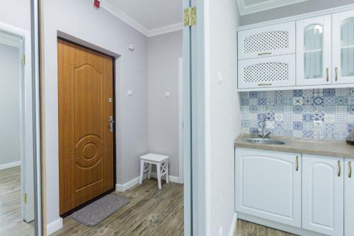 cocina con armarios blancos y puerta marrón en Cosy Apartment at Pozniaky, en Kiev