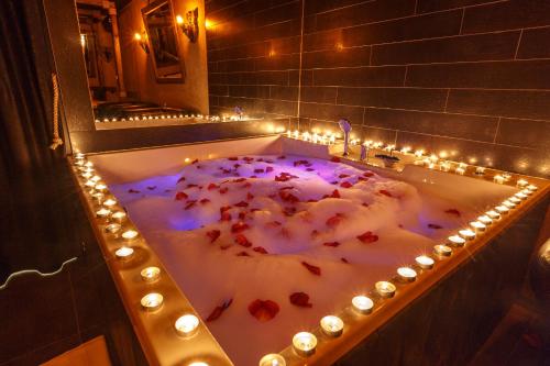 a bath tub filled with candles and red flowers at Rooms Apartments in Samara