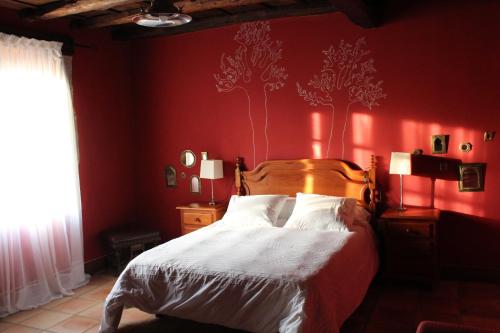 a bedroom with a bed with a red wall with trees on it at Rectoral de Anllo in Sober