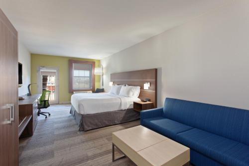 a hotel room with a bed and a blue couch at Holiday Inn Express & Suites Corona, an IHG Hotel in Corona
