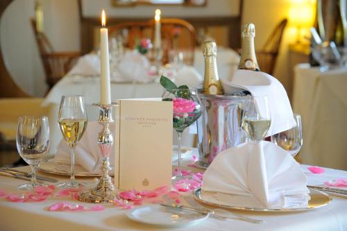 a table with two candles and wine glasses on it at Romantik Waldhotel Mangold in Bergisch Gladbach