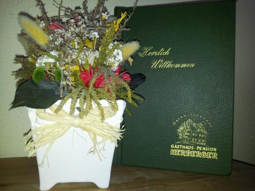 um vaso branco cheio de flores ao lado de um passaporte em Gasthaus-Pension Herberger em Kurort Oberwiesenthal