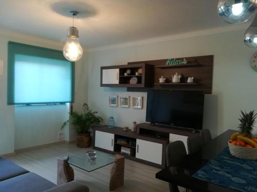 a living room with a couch and a television at Casas Da Roseira 2+1 Famalicao Nazare in Nazaré