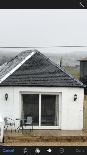 a white house with a table and chairs on it at Carriage Cottage Hot Tub in Beith