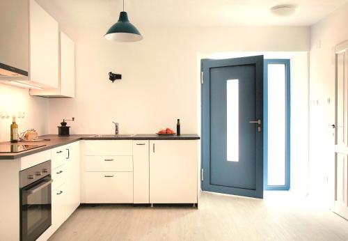 eine Küche mit weißen Schränken und einer blauen Tür in der Unterkunft Apartmani Harmonija in Žman