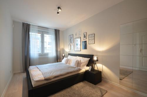 Schlafzimmer mit einem Bett, einem Fenster und einem Teppich in der Unterkunft Apartamenty-Plaza Kołobrzeg in Kołobrzeg