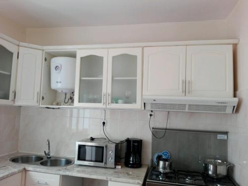 een keuken met witte kasten en een magnetron bij Casa Mendes in Tarrafal